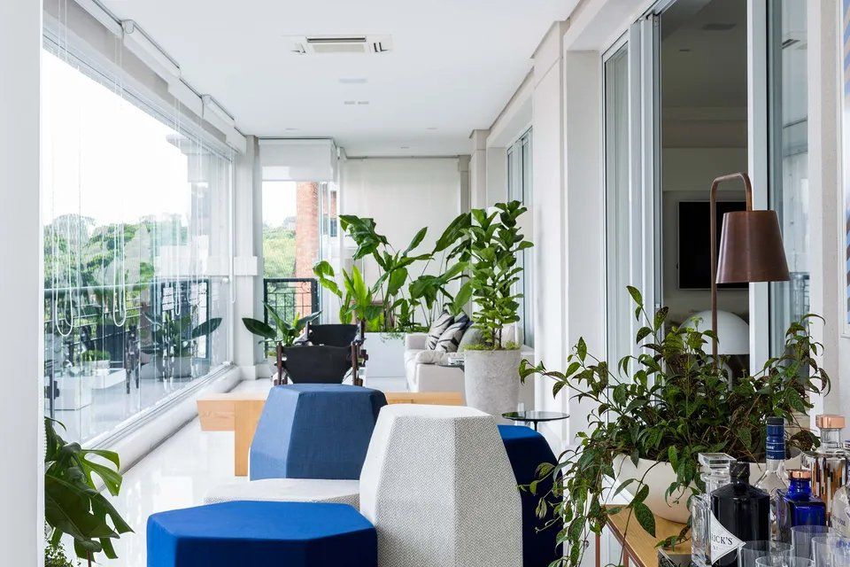 Uma sala de estar com muitas janelas e plantas