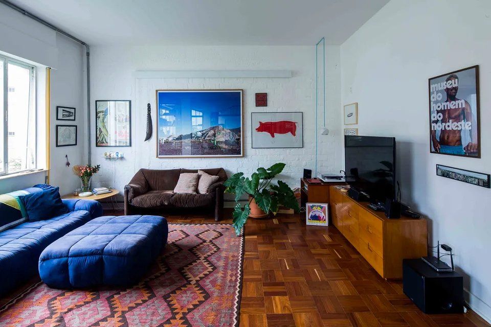 Uma sala de estar com sofá, pufe e televisão.