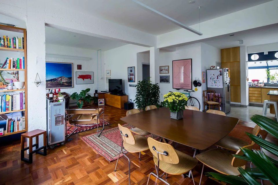 Uma sala de estar com mesa e cadeiras de madeira e uma estante.