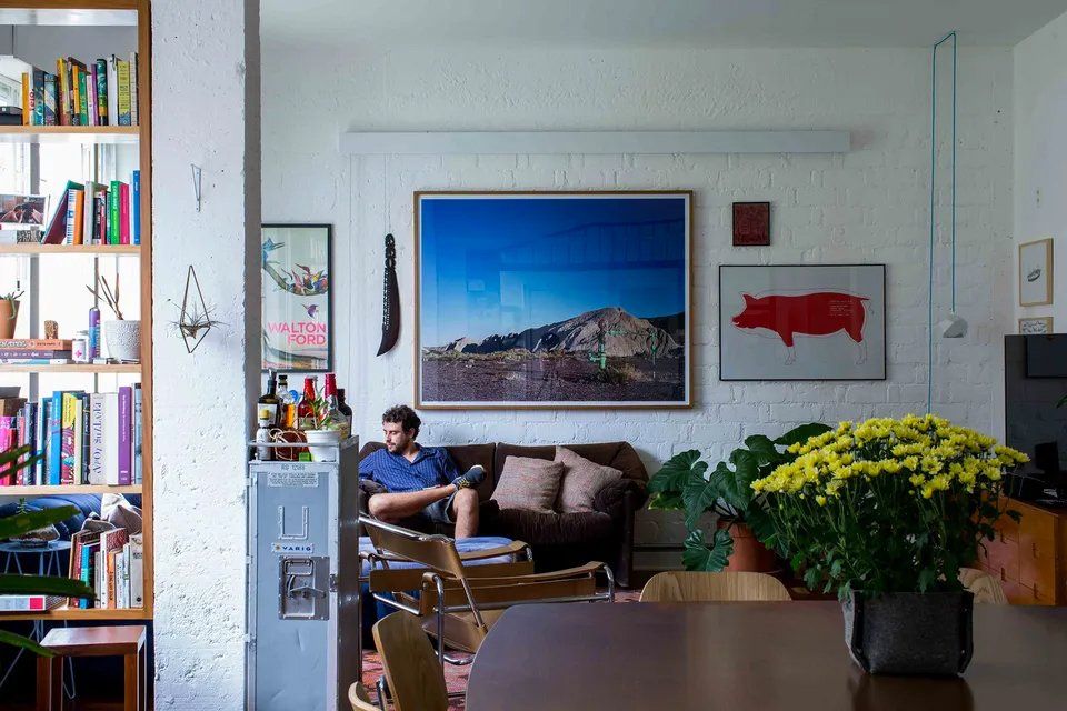 Um homem está sentado no sofá de uma sala de estar.