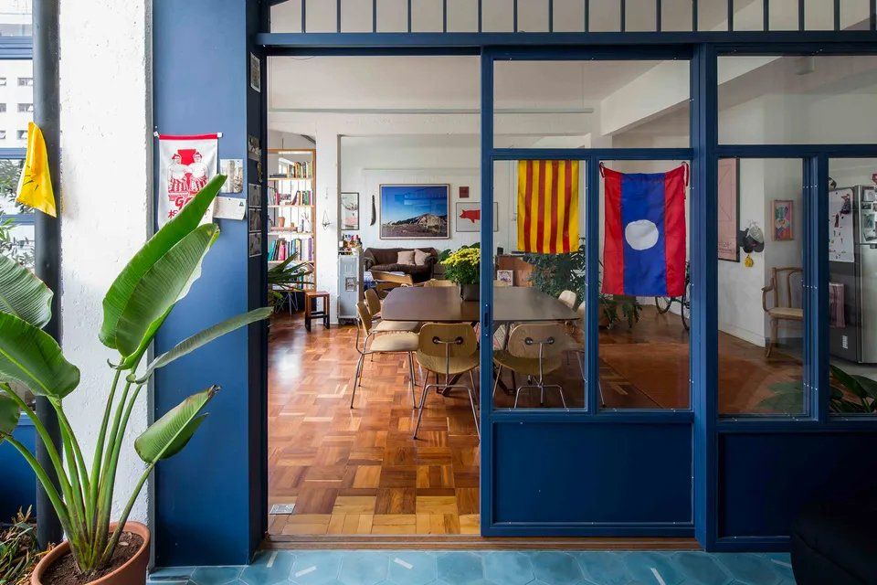 Uma sala de estar com uma porta azul e uma porta de vidro deslizante que dá acesso a uma sala de jantar.