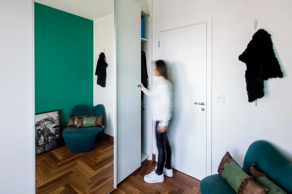 Uma mulher está em uma sala olhando dentro de um armário.