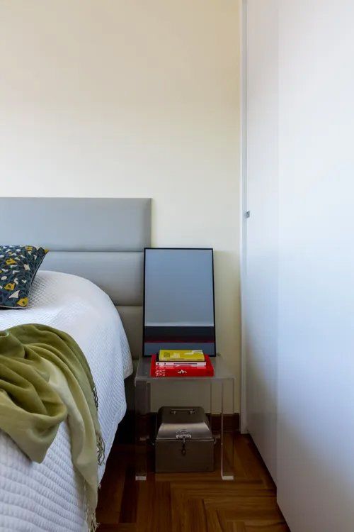 Um quarto com uma cama e uma mesa de cabeceira com livros.