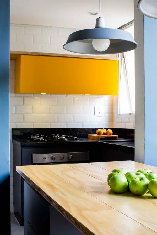 Uma cozinha com armários amarelos e bancada de madeira