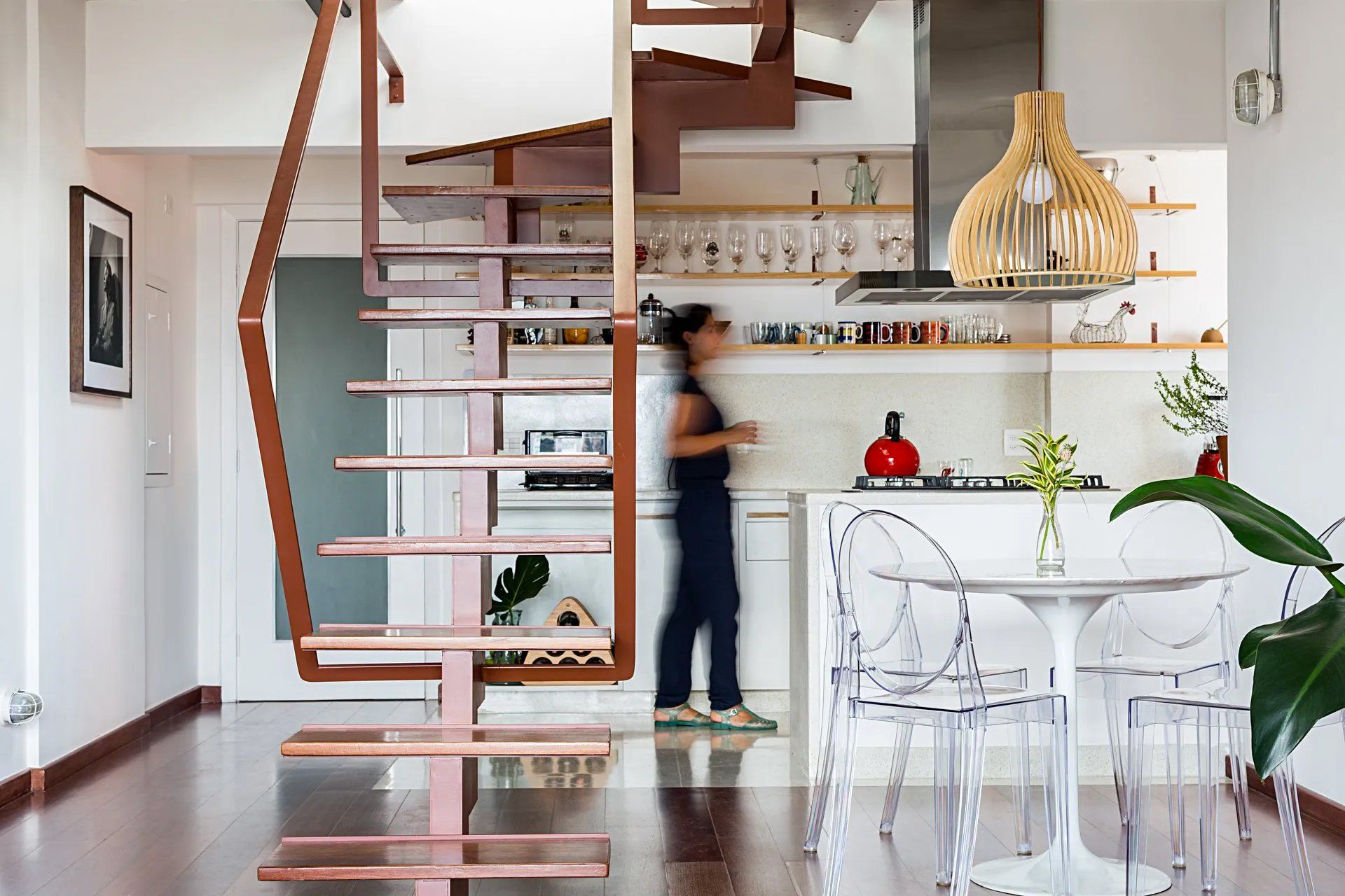 Uma mulher está descendo uma escada de madeira em uma cozinha.
