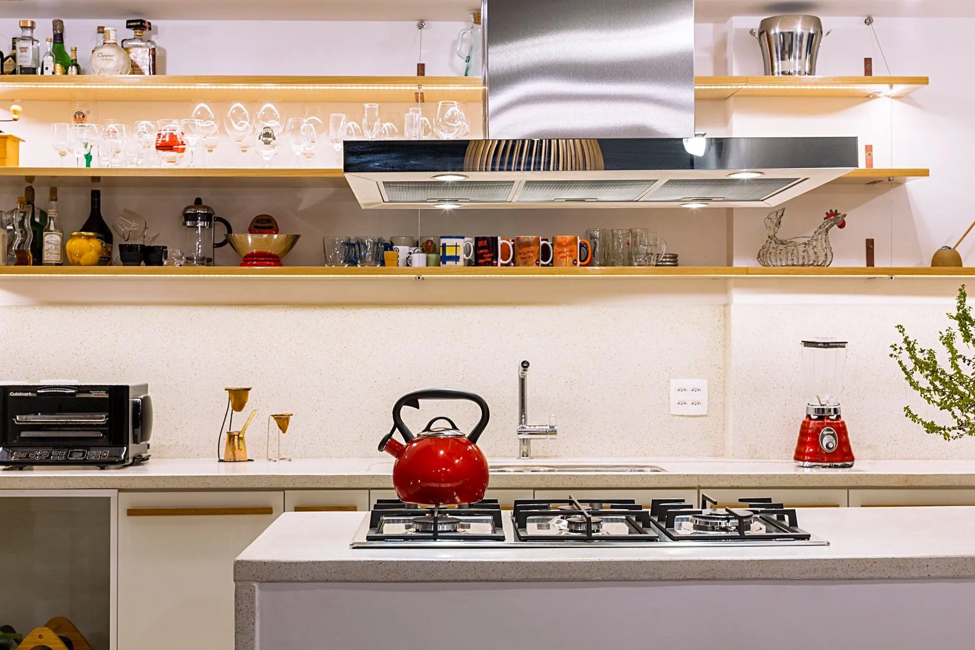 Uma cozinha com uma chaleira vermelha no fogão.