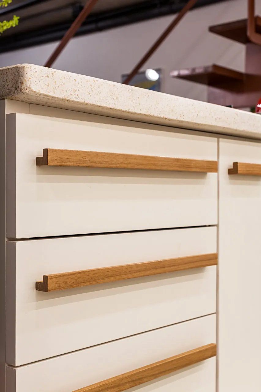 Um close de um armário branco com alças de madeira