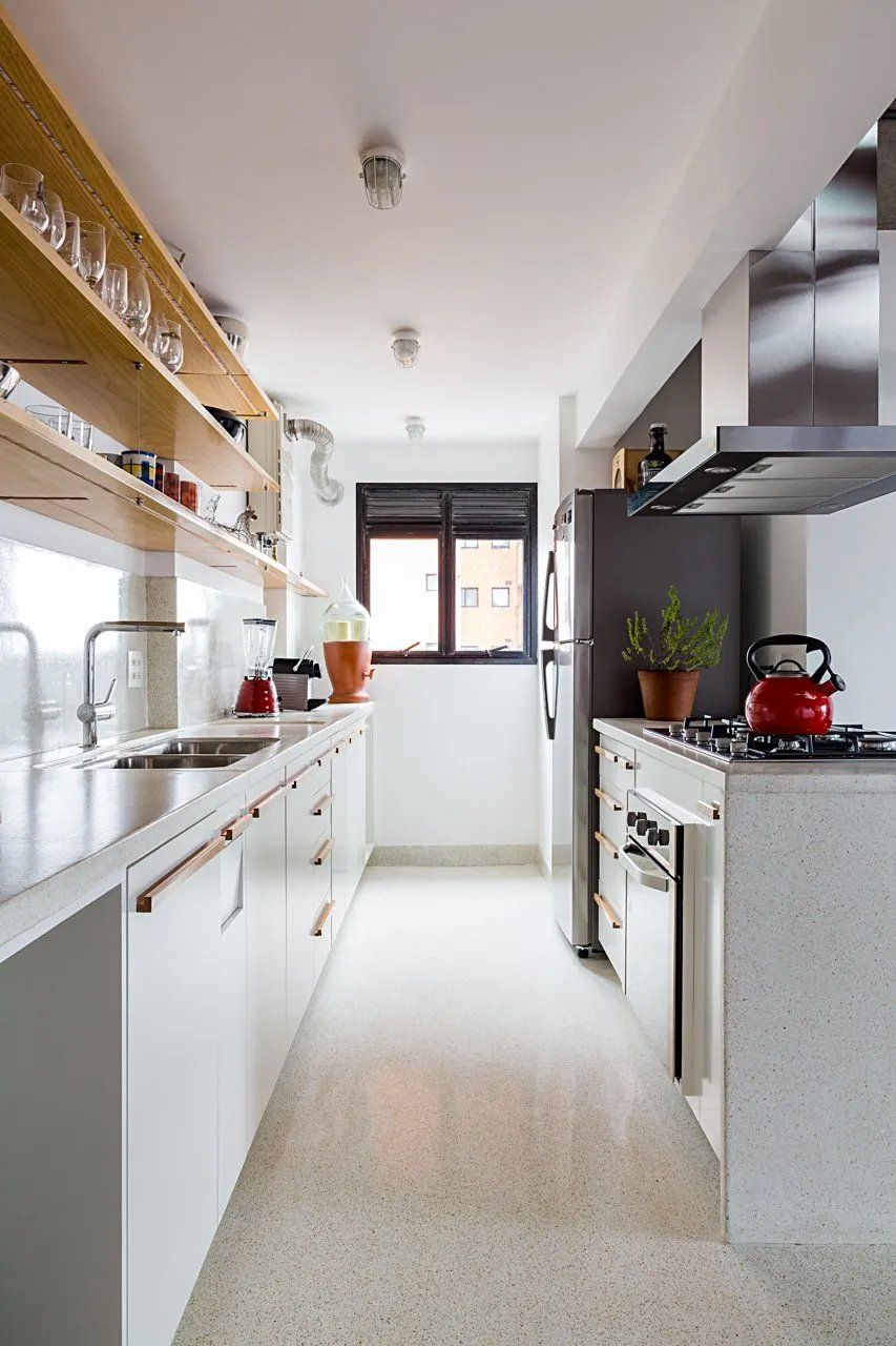 Uma cozinha com armários brancos, fogão, geladeira e pia.