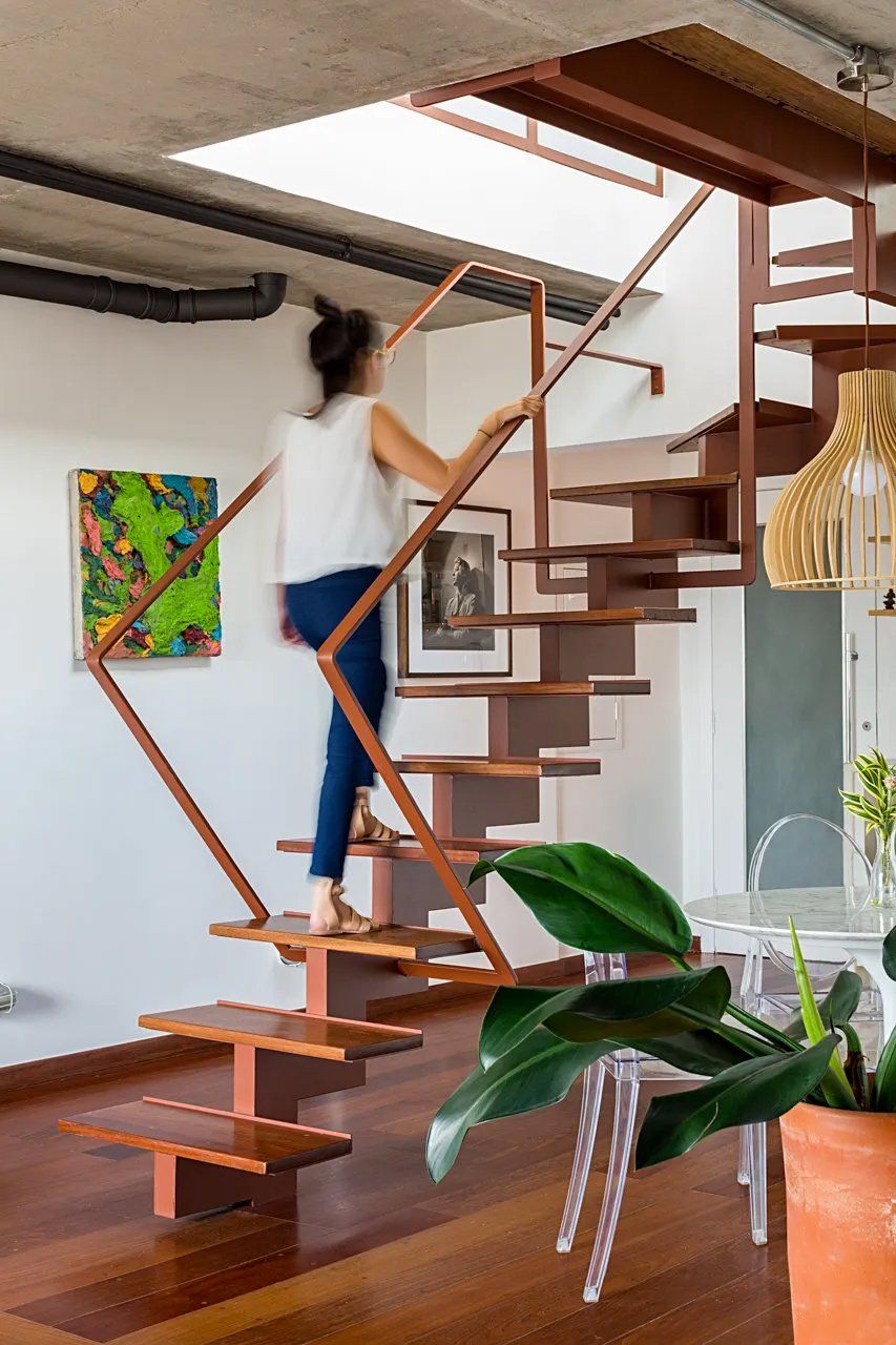 Uma mulher está subindo uma escada de madeira em uma sala de estar.