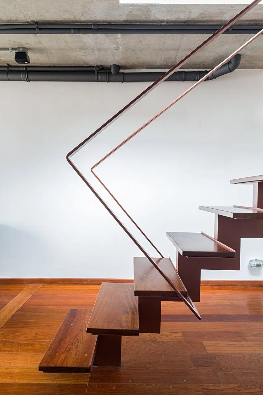 Uma escada de madeira com corrimão de metal em uma sala