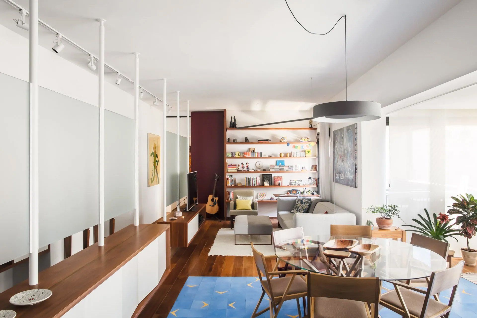 Uma sala de estar com mesa e cadeiras de jantar e um violão na parede.