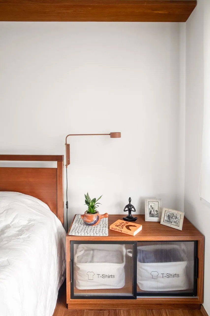 Um quarto com uma cama e uma mesa de cabeceira com cestos.