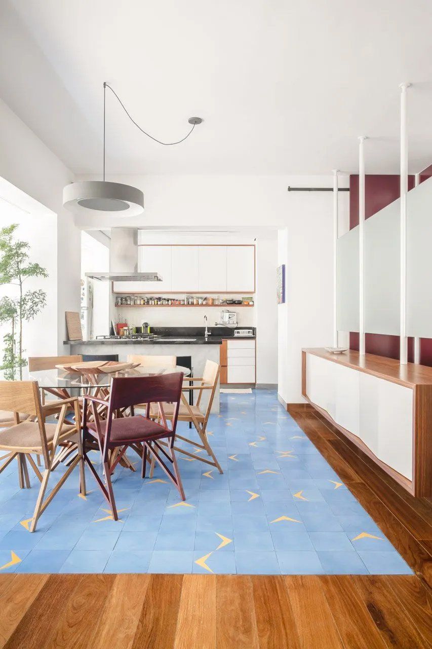 Uma sala de jantar com mesa e cadeiras e um tapete azul no chão.