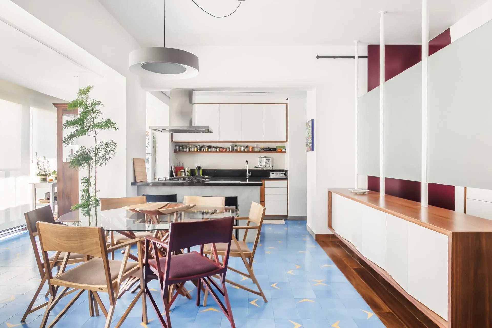 Uma sala de jantar com mesa e cadeiras e uma cozinha ao fundo.