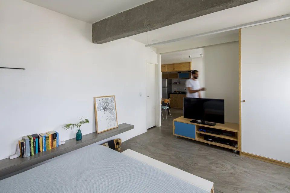 Um homem está parado em uma sala de estar ao lado de uma televisão.