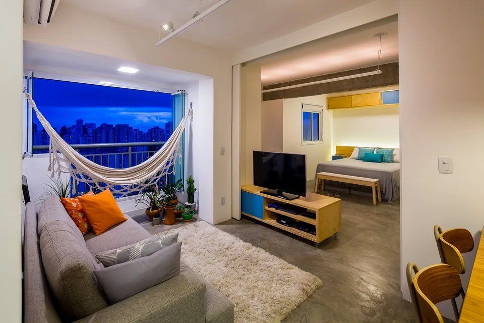 Uma sala com sofá, televisão e rede.