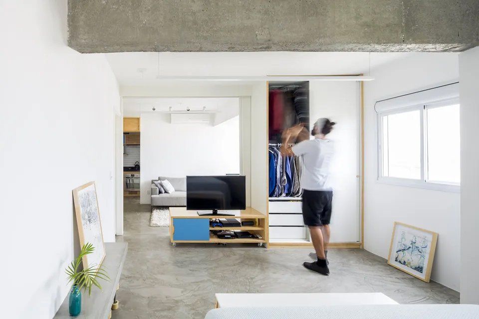 Um homem está parado em uma sala olhando dentro de um armário.