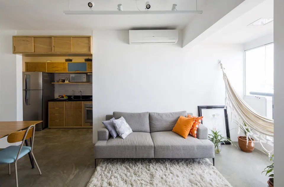 Uma sala com sofá, rede, mesa e cadeiras.