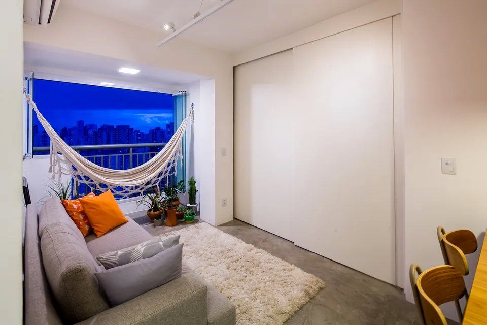 Uma sala com sofá e rede na varanda.