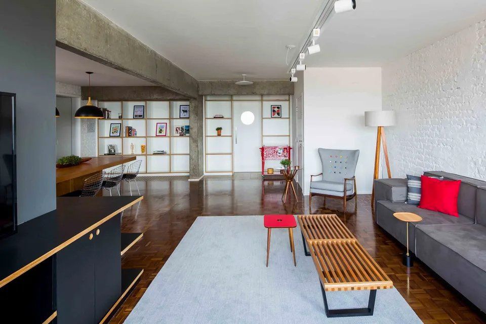 Uma sala de estar com sofá, cadeira, mesa e estantes.