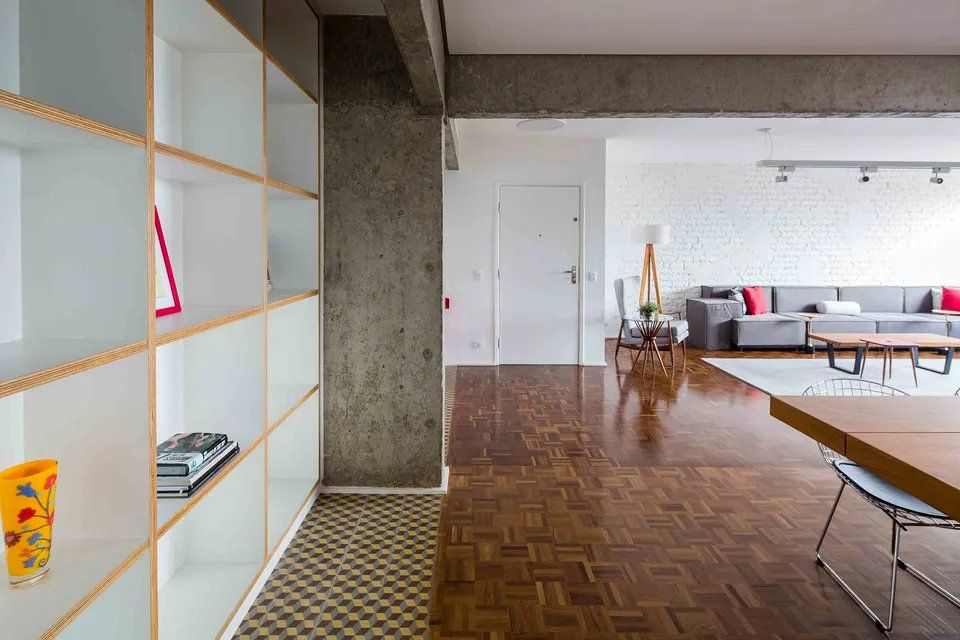 Uma sala com sofá, mesa, cadeiras e estantes.