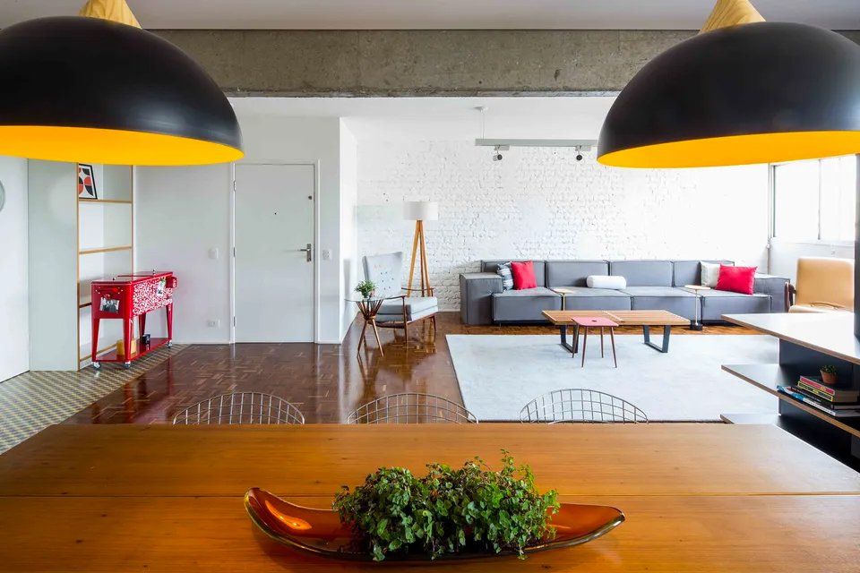 Uma sala de estar com sofá, mesa de centro e duas luminárias penduradas no teto.