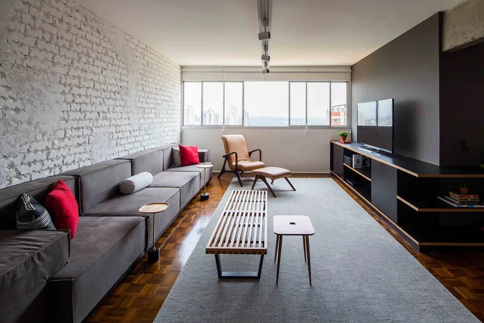 Uma sala com sofá, cadeira, mesa e televisão.