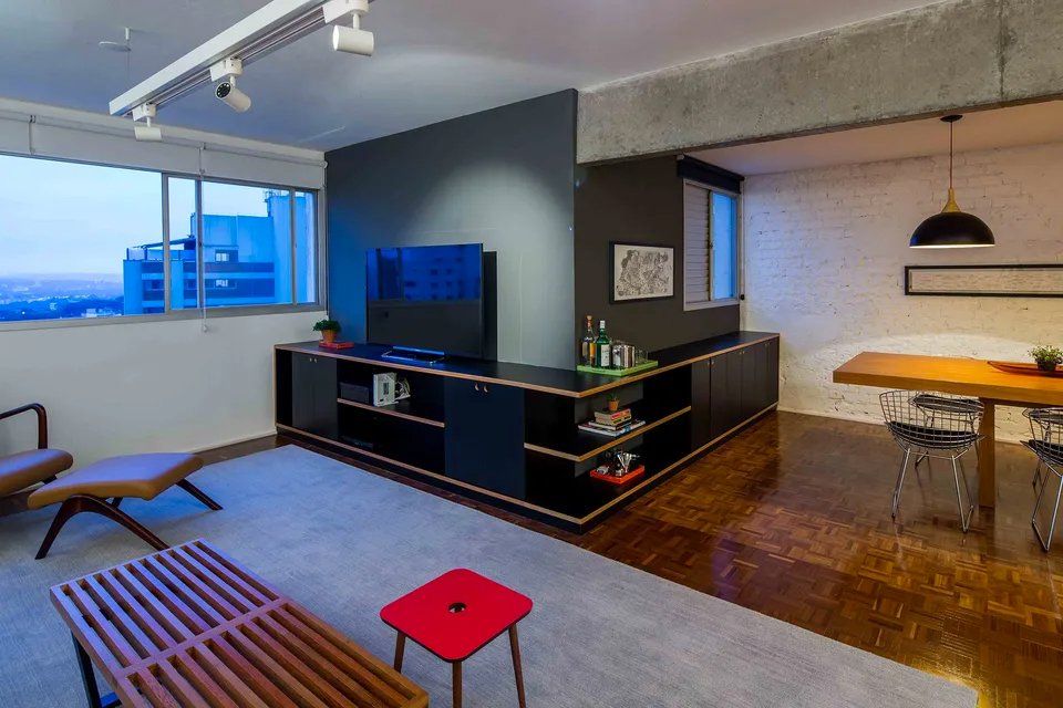 Uma sala de estar com mesa, cadeiras e televisão.