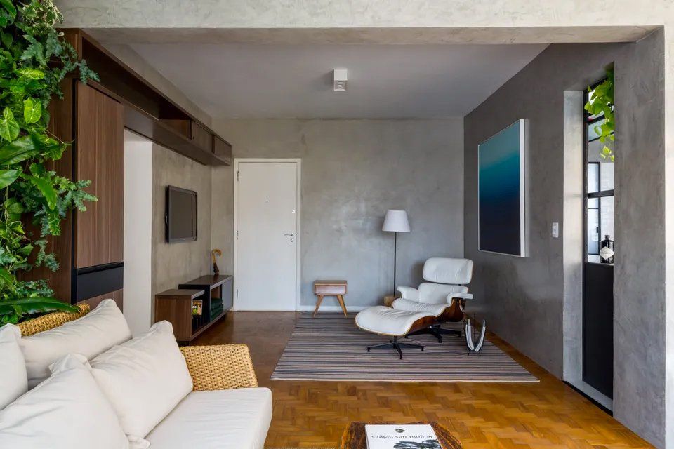 Uma sala de estar com sofá, cadeira e televisão.