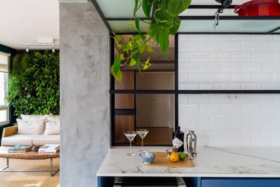 Uma cozinha com duas taças de martini no balcão e uma sala ao fundo.