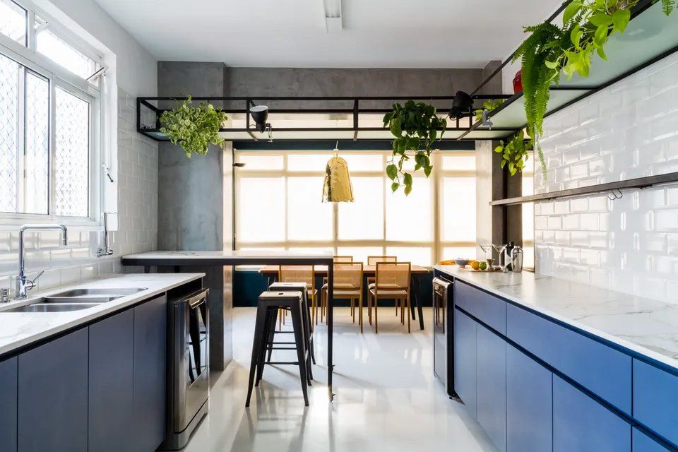 Uma cozinha com armários azuis, pia, mesa e cadeiras.