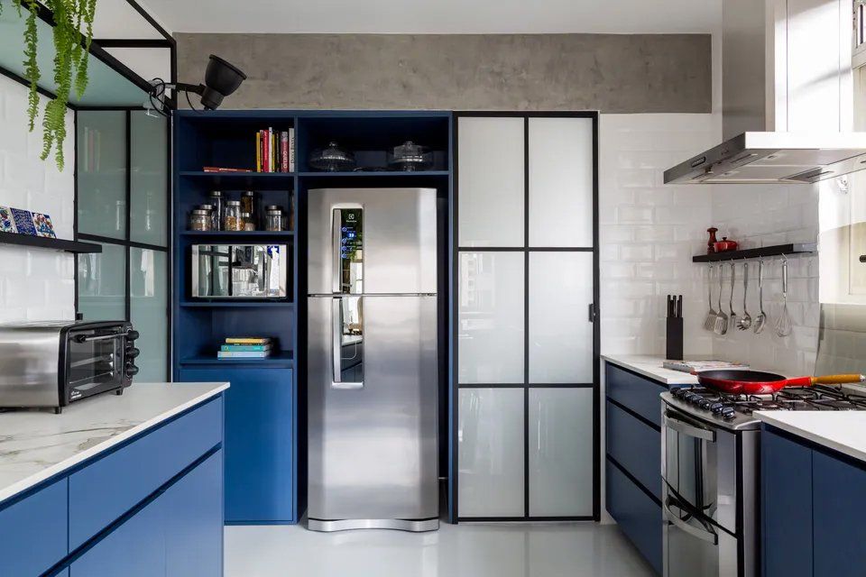 Uma cozinha com armários azuis e geladeira de aço inoxidável.
