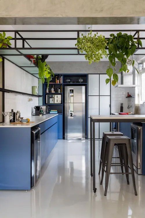 Uma cozinha com armários azuis, mesa e banquetas.