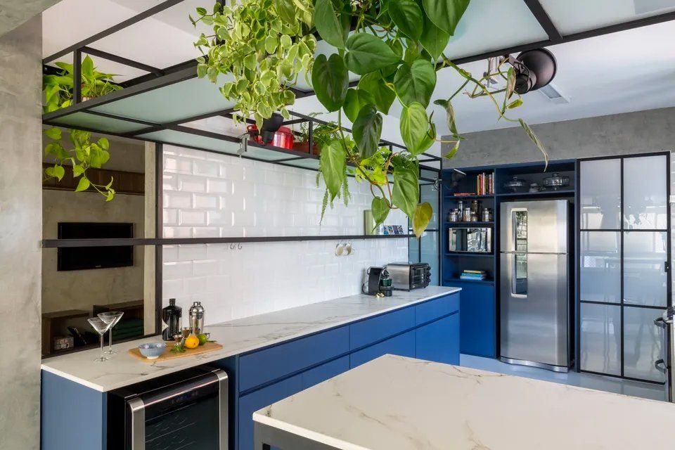 Uma cozinha com armários azuis e geladeira de inox.