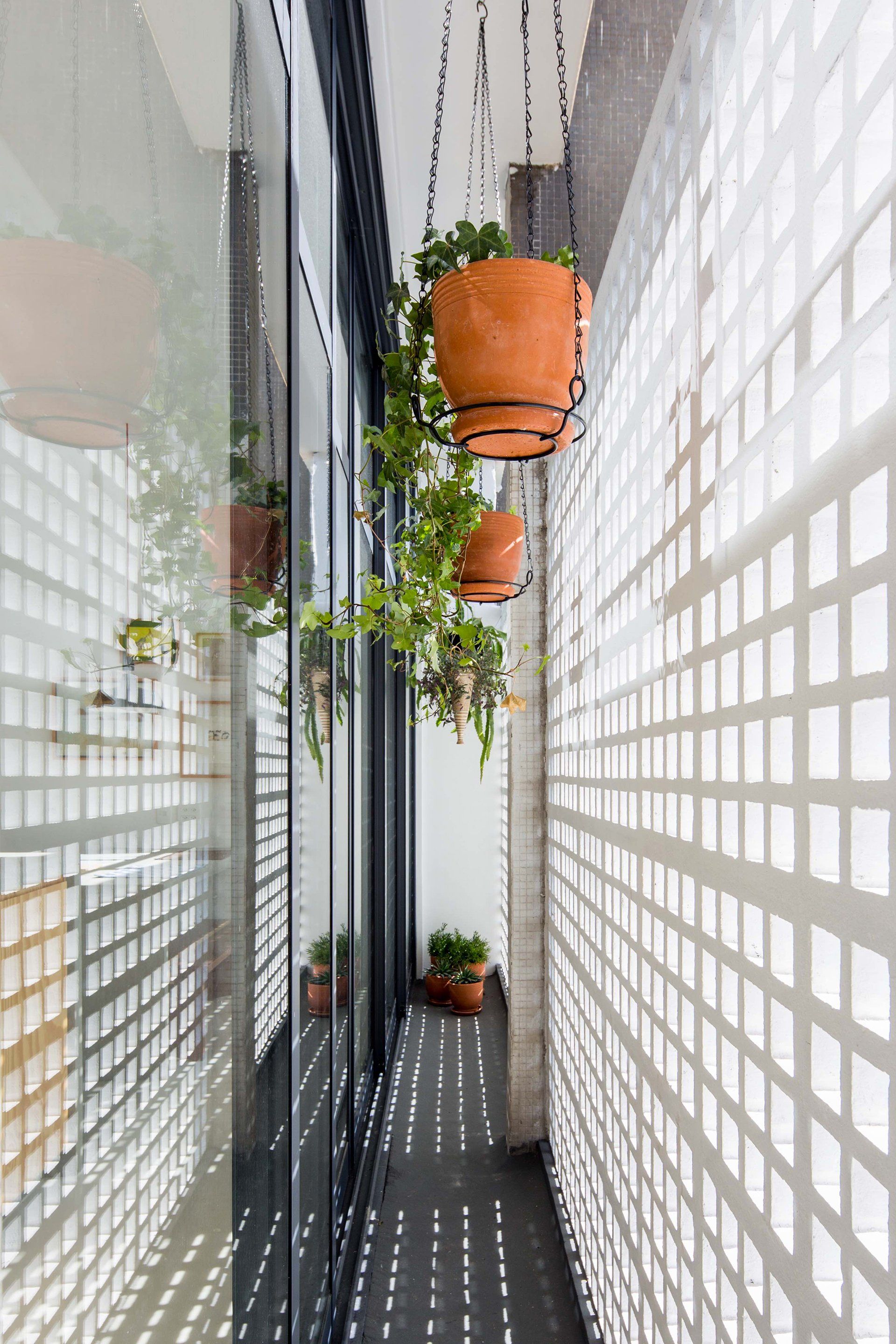 Um longo corredor com vasos de plantas pendurados no teto.