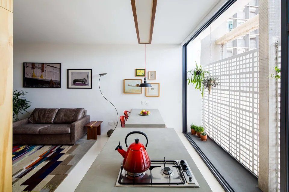 Uma cozinha com uma chaleira vermelha no fogão.