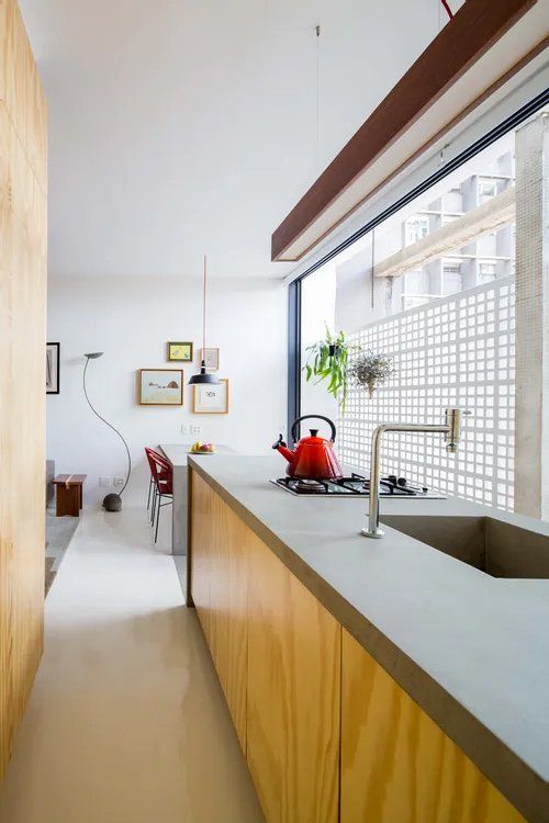 Uma cozinha com armários de madeira e uma pia com uma chaleira vermelha no fogão.