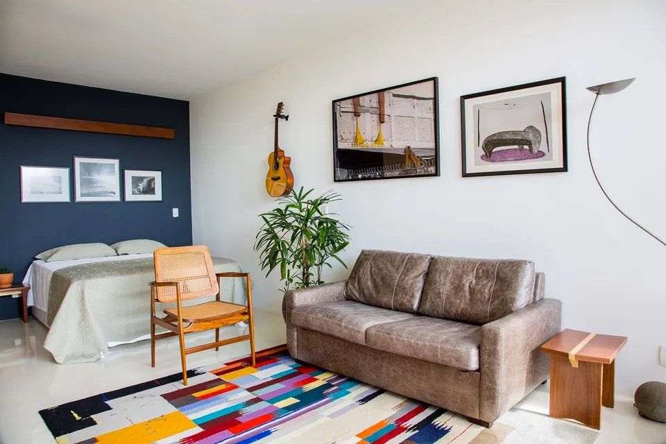 Uma sala de estar com sofá, cadeira e cama.