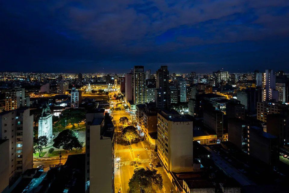Uma vista aérea de uma cidade à noite com muitos prédios iluminados.