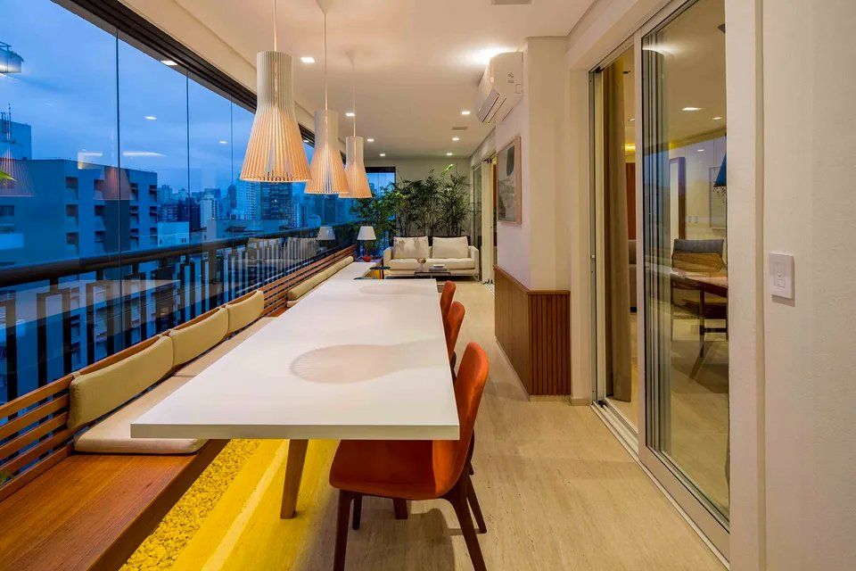 Há uma longa mesa e cadeiras na varanda.