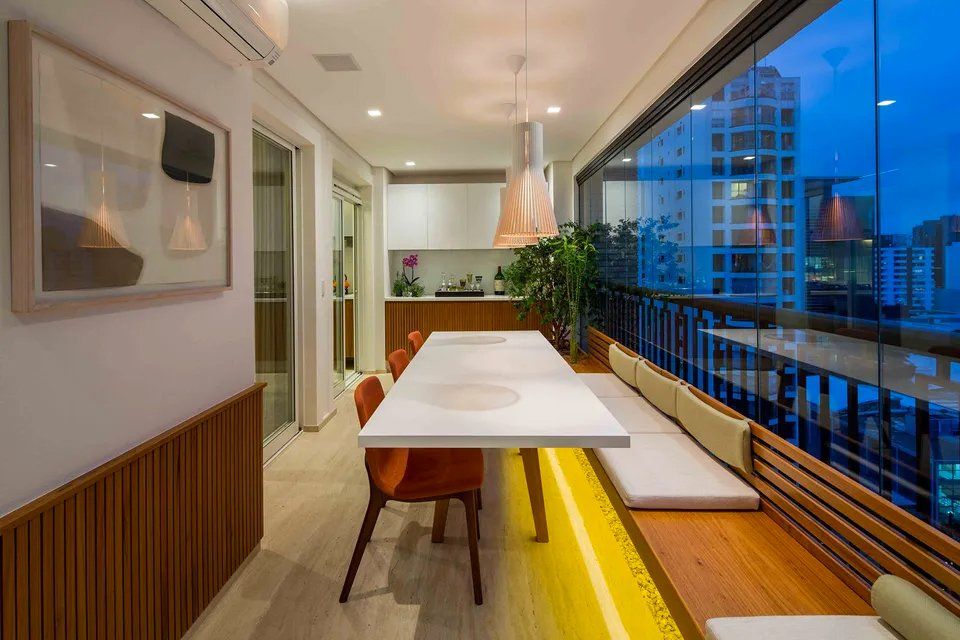 Há uma longa mesa e cadeiras na varanda.