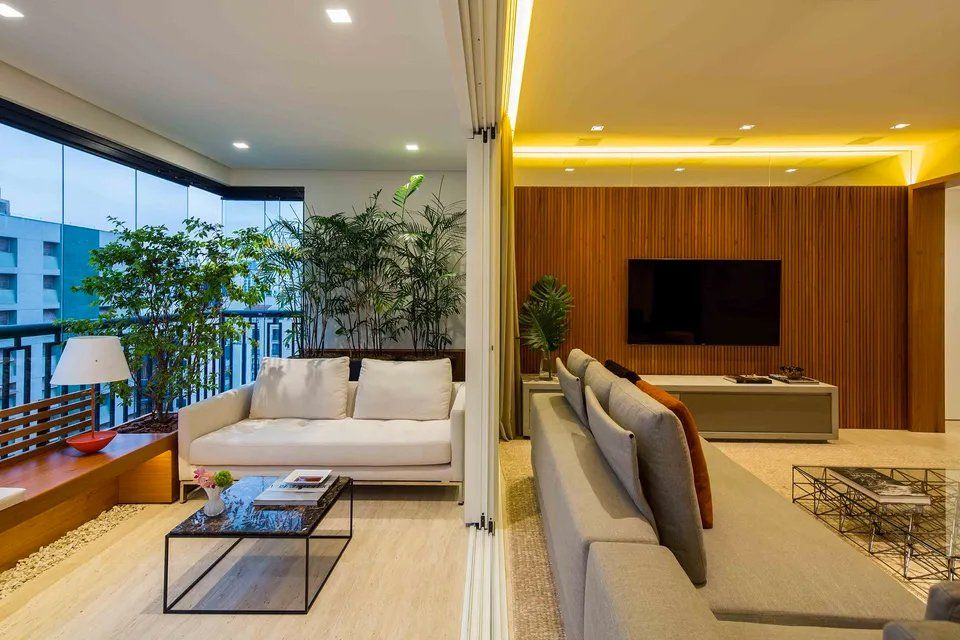 Uma sala com sofá, mesa de centro, televisão e varanda.