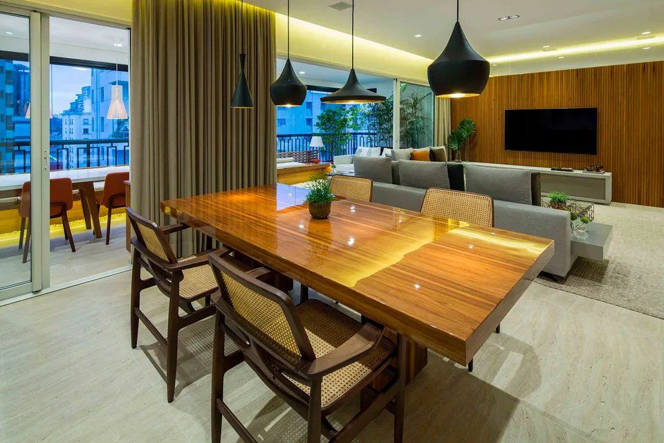 Uma sala de jantar com mesa e cadeiras de madeira e uma TV de tela plana.