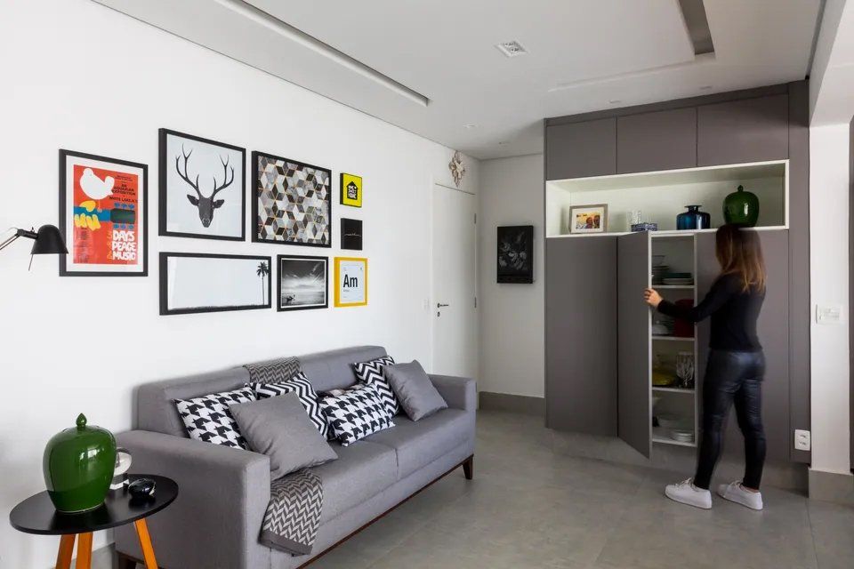 Uma mulher está abrindo um armário em uma sala com um sofá.