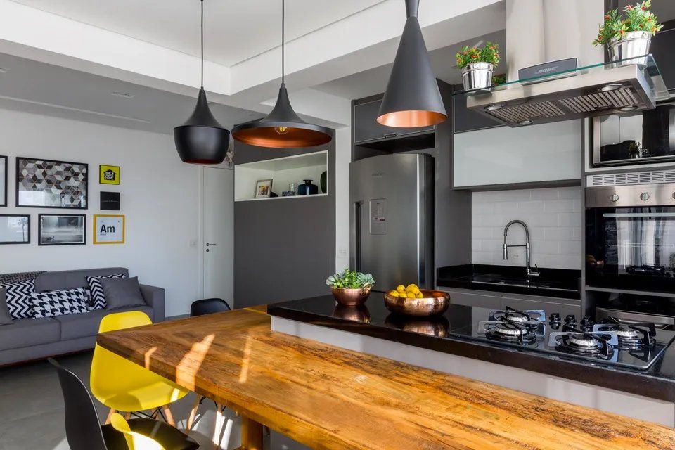 Uma cozinha com mesa de madeira e bancadas pretas.