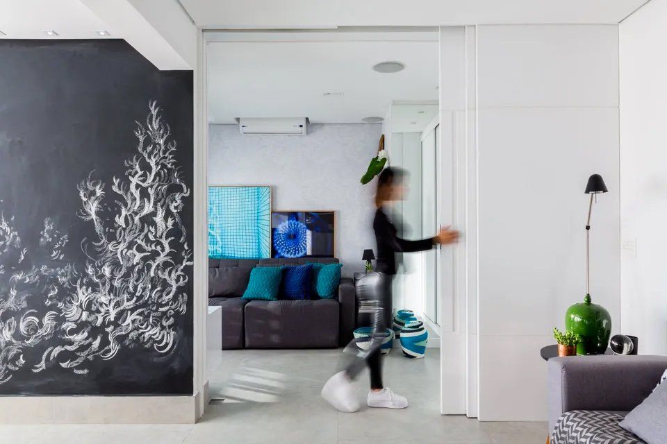 Uma mulher está entrando em uma sala de estar com um quadro-negro na parede.