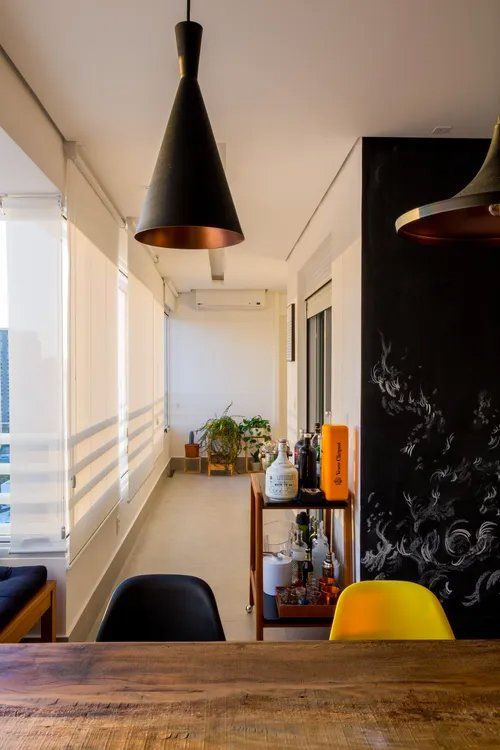 Um longo corredor com uma mesa e cadeiras de madeira que dá acesso a uma varanda.