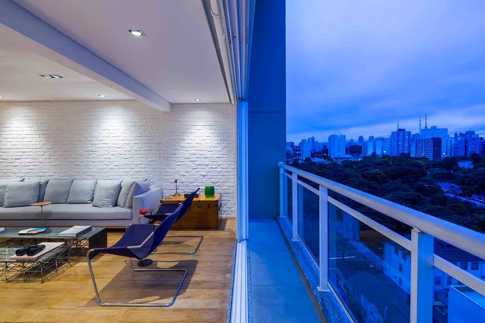 Uma sala de estar com sofá e cadeiras e uma varanda com vista para a cidade.