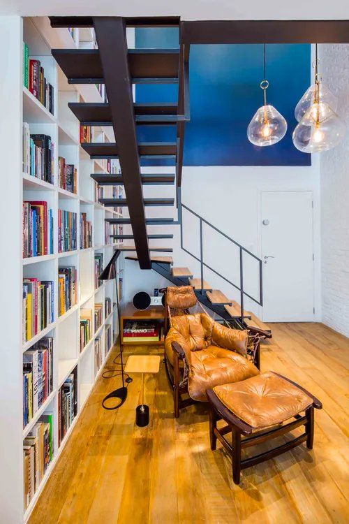 Uma sala com escada que dá acesso ao segundo andar.