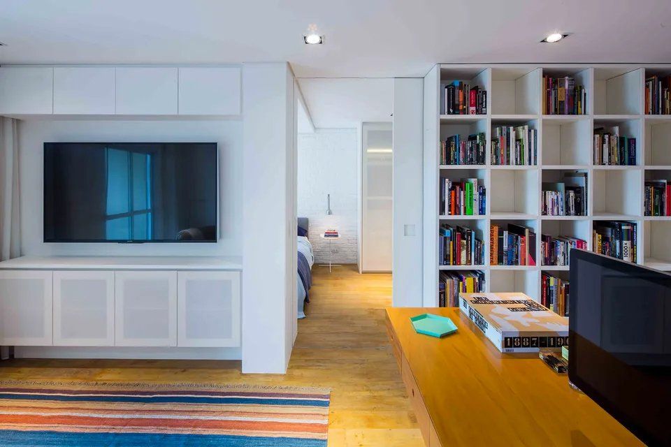 Uma sala de estar com uma TV de tela plana e uma estante.
